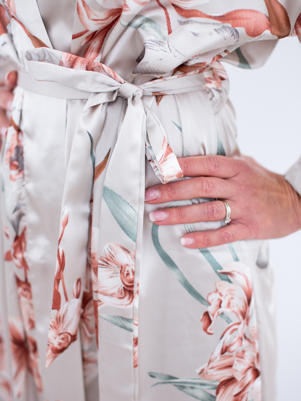 Woman wearing satin robe in floral, close-up of tie, hand on hip
